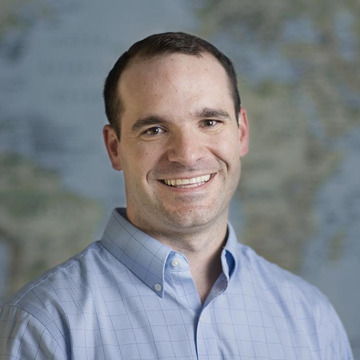 Dr. Jeff Lane headshot in front of world map.